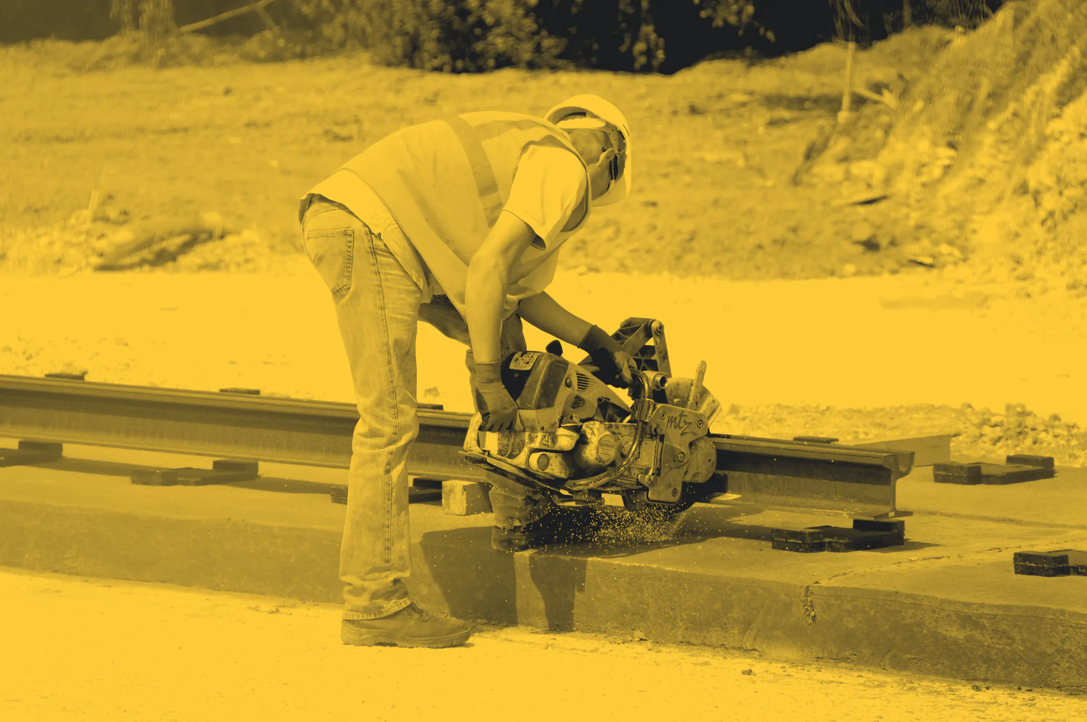 A worker in hi-vis and a hard hat cutting steel with a cut-off saw, sparks flying