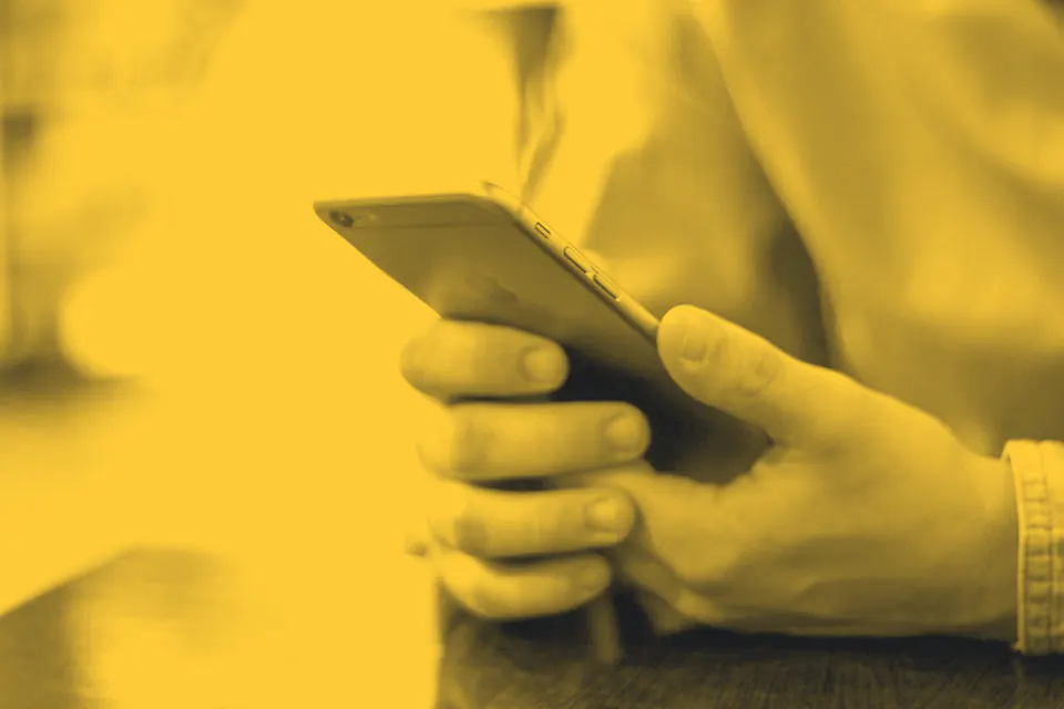 Hands holding a smartphone over a desk