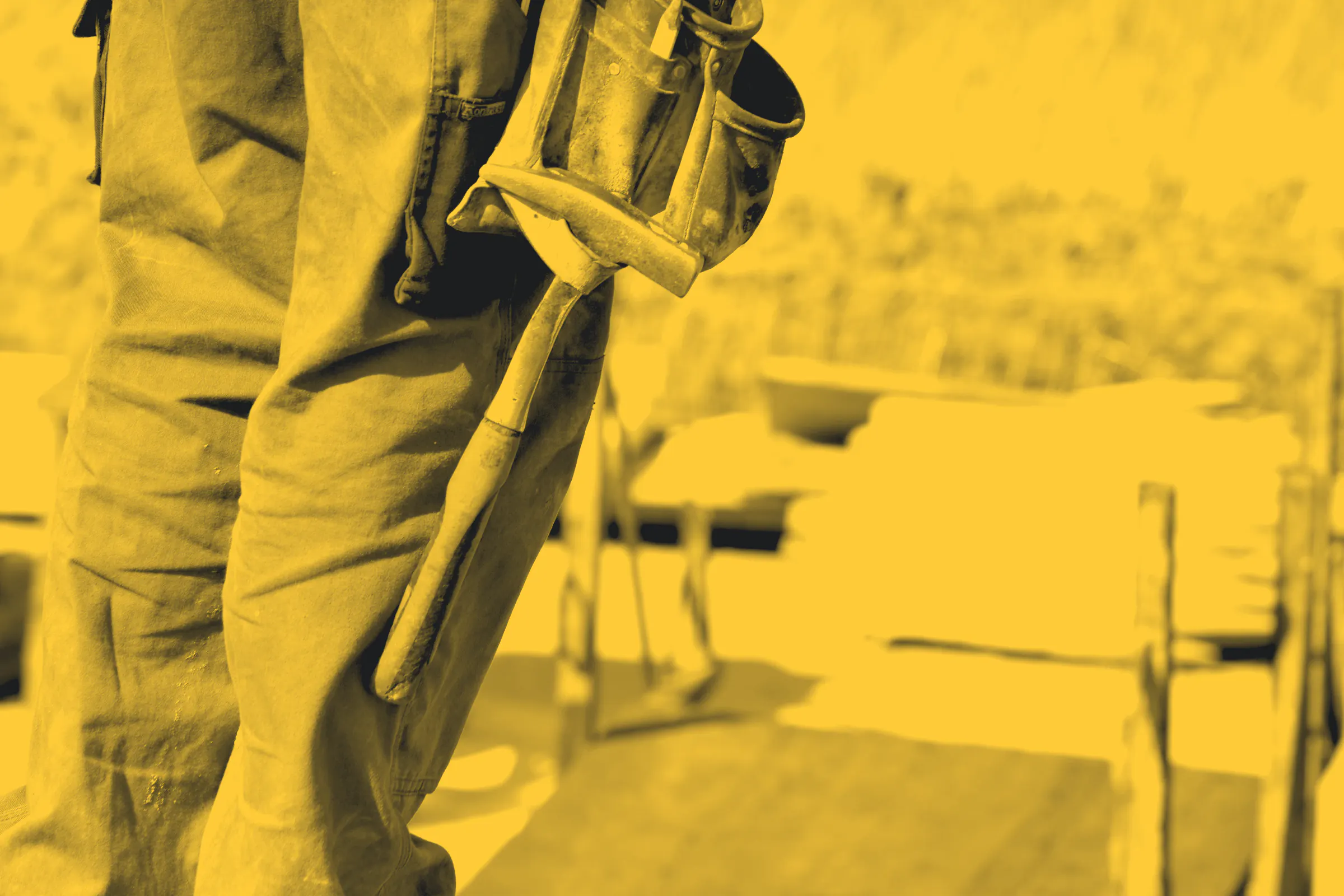A hammer and pouch on a tool belt, with stacked timber behind